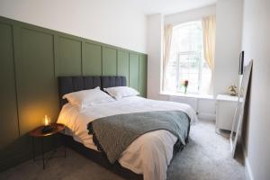 a bedroom with a large bed with a green headboard at Litton Mill Retreat, Luxury Converted Mill in Cressbrook