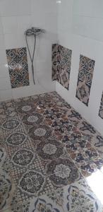 a bathroom with a tile floor with a shower at Dar Mamina in Sīdī ash Shammākh