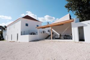 ein weißes Gebäude am Strand neben einem Haus in der Unterkunft Azoia 10 - Casas de Campo & Hostel in Azoia de Baixo