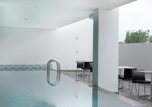 a pool with chairs and tables in a building at Amaris Hotel Malang in Malang