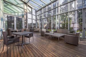 un giardino d'inverno con tavoli, sedie e finestre di Hotel For You a Cernusco sul Naviglio