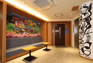 姫路市にあるTabist カプセルホテルAPODS 姫路駅前の大きな絵画が壁に描かれたロビー