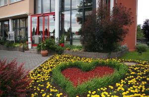 a heart in a bed of flowers in front of a building at Hotel Antares in Halberstadt