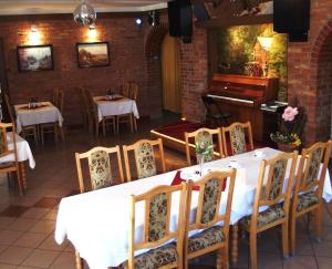 a dining room with a table and a piano at Hotelik Mazury in Olecko