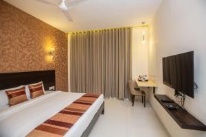 a hotel room with a bed and a desk and a television at Hotel Singh`s By WB Inn, Vashi, Navi Mumbai in Navi Mumbai