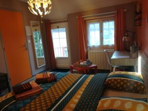 a bedroom with a bed and a table and windows at La cité des abeilles in Villemandeur