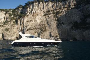 a white boat in the water next to a cliff at Gianetti 50' HT in Sorrento