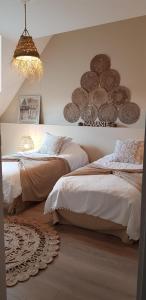 a bedroom with two beds and a chandelier at La grange du bois in Fresnicourt-le-Dolmen