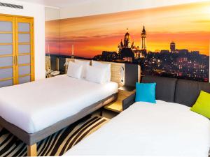 two beds in a room with a view of a city at Novotel Paris 14 Porte d'Orléans in Paris