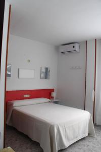 a bedroom with a white bed with a red headboard at Hostal Las Dunas in El Cabo de Gata