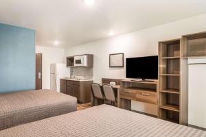 a hotel room with two beds and a desk with a television at WoodSpring Suites Atlanta Newnan in Newnan