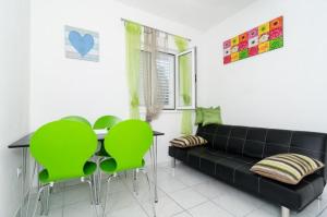 a living room with a black couch and green chairs at Apartments Ammos in Saplunara
