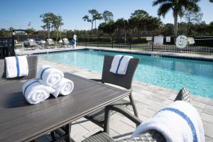 a table and chairs next to a swimming pool at Holiday Inn Express & Suites - Fort Myers Airport, an IHG Hotel in Fort Myers