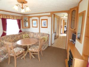 a living room with a couch and a table and chairs at DISABLED ACCESS Orchards 21 at Southview Leisure Park in Lincolnshire