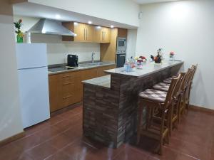 a kitchen with a bar with chairs and a white refrigerator at Casa da Tia Bina in Castelo de Paiva