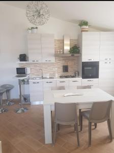 cocina con armarios blancos, mesa y sillas en La Casa Delle Rose 2 en Giba