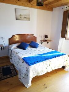 - une chambre avec un grand lit et des oreillers bleus dans l'établissement Vivienda Vacacional Los Picuos - Casas de los Picos, à Robriguero