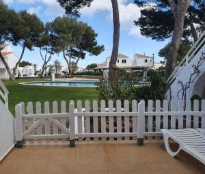 ein weißer Gartenzaun mit einem Pool im Hintergrund in der Unterkunft Villa Pilar in Es Mercadal