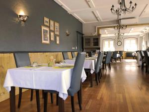 una sala da pranzo con tavoli bianchi e sedie nere di Le rendez-vous des Copains a Logelheim