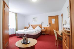 
a hotel room with two beds and a table at Land-gut-Hotel Landgasthof zur Rose in Ehingen
