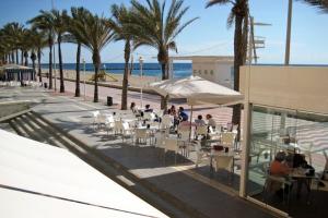 un grupo de personas sentadas en un restaurante cerca de la playa en Hostal Delfin Verde, en Almería