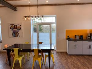 a kitchen with a dining room table and yellow chairs at Altes Bahnhofsvorsteherhaus in Husum