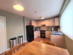cocina con mesa de madera y nevera negra en 3 Bedroom Apartment Coventry - Hosted by Coventry Accommodation en Coventry