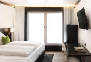 a bedroom with a bed and a television and a window at KL Hotel by WMM Hotels in Kaiserslautern
