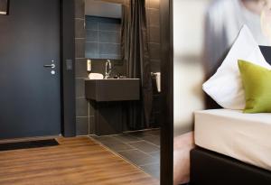 Baño con lavabo junto a una cama con lavamanos en KL Hotel by WMM Hotels, en Kaiserslautern