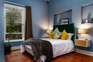 Un dormitorio con una cama con paredes azules y una ventana en Obz Hotel, en Ciudad del Cabo