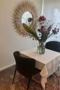 una mesa con un jarrón de flores y un espejo en VILLA FER-GUY " Beeldige Suite met parking, nabij strand en casino", en Knokke-Heist