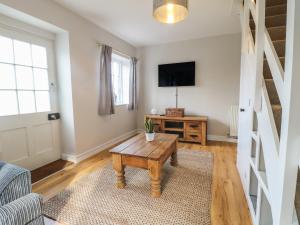 a living room with a table and a tv at Paddock View Cottage in Grantham