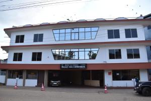 a white building with windows and a parking lot at Hotel City Comforts in Madikeri