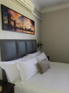 a bed with white pillows and a painting on the wall at Klyne Jiweel Guesthouse in Pretoria