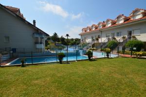 a swimming pool in a yard next to a building at Apartamentos Playa La Arena Encinar in Isla