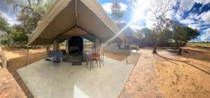 ein Haus mit einem großen Zelt mit einem Tisch und Stühlen in der Unterkunft Limpopo Bushveld Retreat in Vaalwater