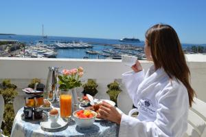 a woman sitting at a table with a cup of coffee at Hotel Splendid in Cannes