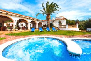 a pool in front of a house with a palm tree at Villa Balneari Resort Casa de vacances familiar in Montroig