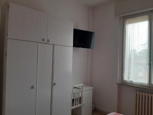 uma sala de estar com uma televisão em cima de um armário branco em Gardenia Guest House em Forlì