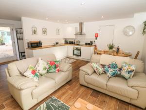 a living room with two couches and a kitchen at Holly Cottage in Sheffield