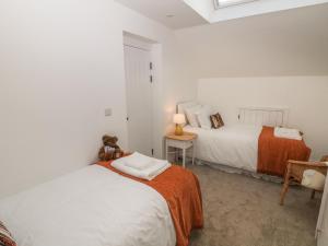 2 Betten in einem weißen Zimmer mit einem Teddybär in der Unterkunft Holly Cottage in Sheffield