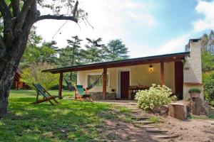 a house with a hammock in front of it at Del Arroyo Cabañas in Villa General Belgrano