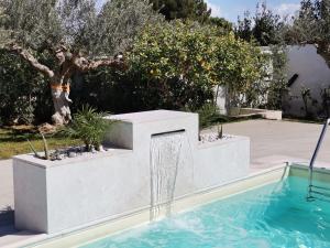 a swimming pool with a water fountain in a yard at Signorino Eco Resort & Spa in Marsala