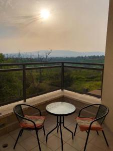 een tafel en 2 stoelen op een balkon met uitzicht bij צימר תות in Qatzrin