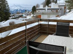 einen Balkon mit einem Tisch und Stühlen im Schnee in der Unterkunft Roc d'Orsay E48 in Leysin