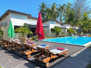 a group of chairs and umbrellas next to a swimming pool at YinDee Lanta Villas in Ko Lanta