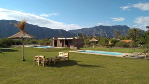 Zonda的住宿－Cabañas Abril，一个带两把椅子和一张桌子的游泳池以及一把遮阳伞