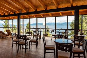 a restaurant with tables and chairs and a view of the water at Hotel Alt Interlaken in San Carlos de Bariloche