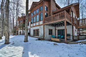 a log home with a deck in the snow at Boyne Falls Hideaway - Walk to Mountain Resort! in Boyne Falls