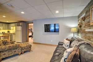 a living room with a couch and a tv on a wall at Boyne Falls Hideaway - Walk to Mountain Resort! in Boyne Falls